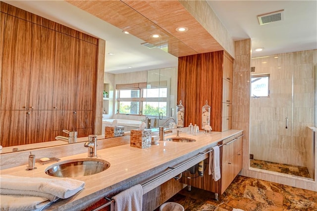 bathroom featuring a stall shower, plenty of natural light, visible vents, and a sink