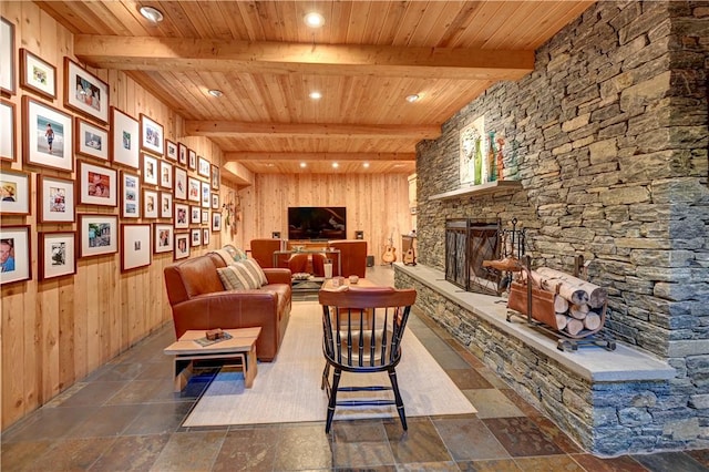 sitting room featuring wooden ceiling, wood walls, beamed ceiling, and a stone fireplace