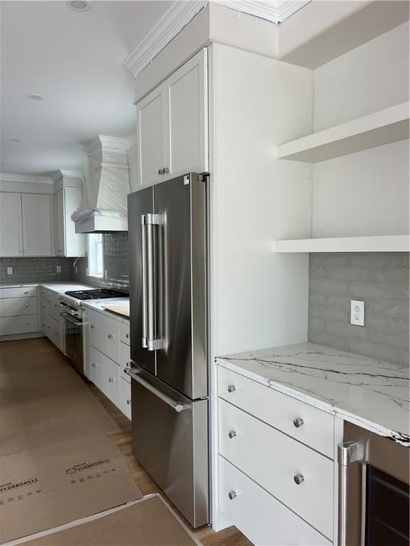 15 Cora St, East Greenwich, RI 02818 - kitchen featuring open shelves, high quality appliances, wall chimney range hood, tasteful backsplash, and light stone countertops