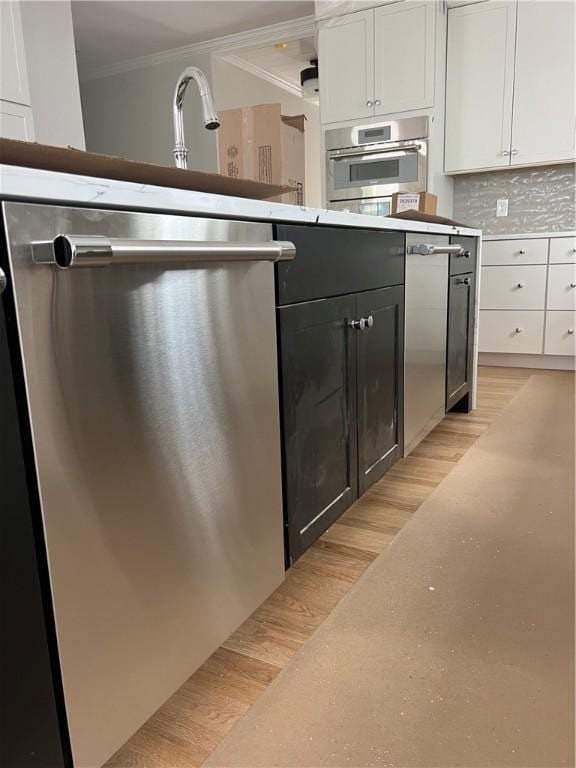 15 Cora St, East Greenwich, RI 02818 - kitchen with stainless steel appliances, crown molding, white cabinetry, decorative backsplash, and light countertops