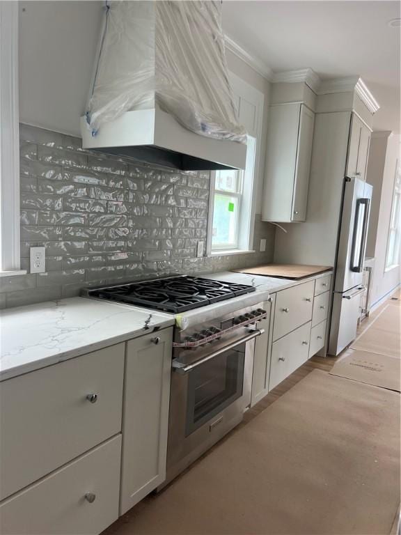 15 Cora St, East Greenwich, RI 02818 - kitchen featuring high end appliances, premium range hood, backsplash, white cabinetry, and crown molding
