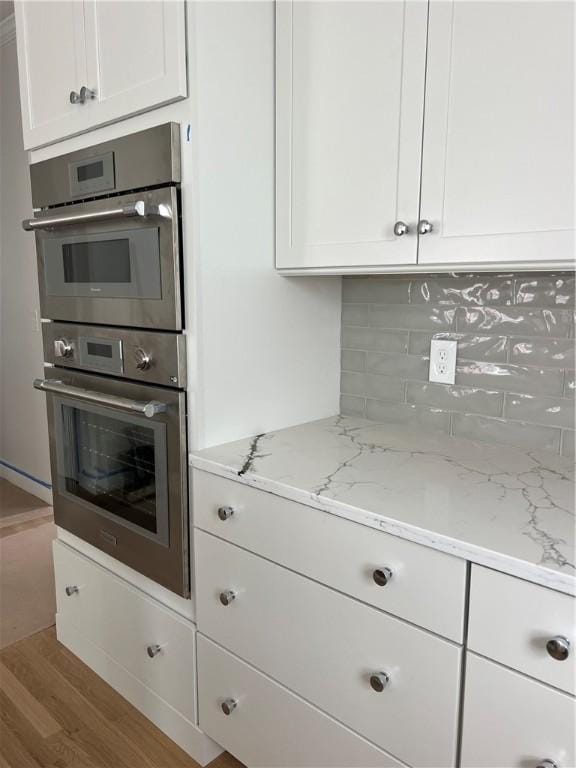 15 Cora St, East Greenwich, RI 02818 - kitchen featuring stainless steel double oven, wood finished floors, white cabinets, and backsplash