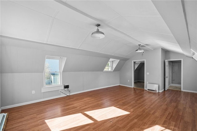 bonus room featuring wood-type flooring, heating unit, vaulted ceiling, and a healthy amount of sunlight