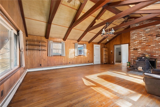 unfurnished living room featuring wooden walls, a baseboard radiator, and a wood stove