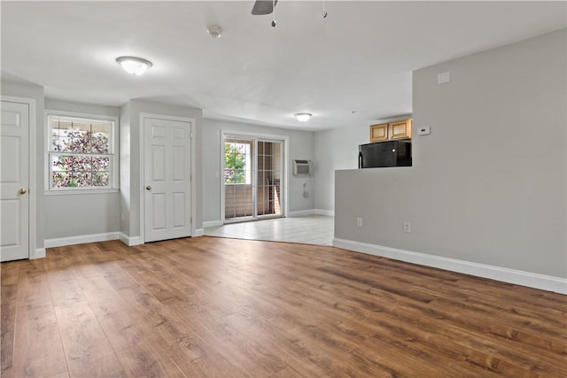 empty room with ceiling fan, light hardwood / wood-style floors, and a wall unit AC