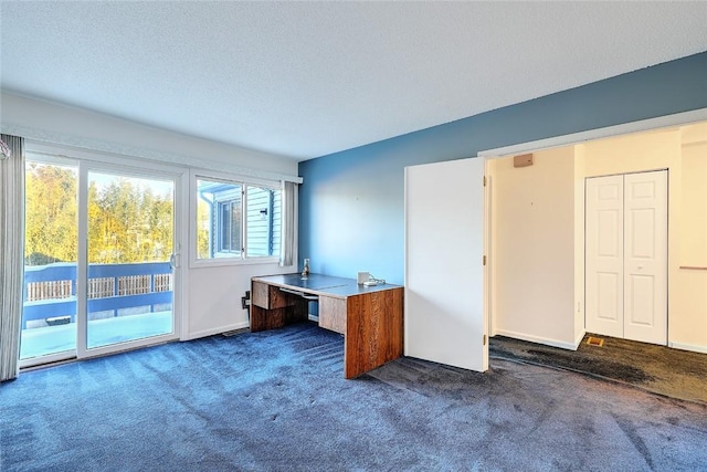 unfurnished office featuring dark colored carpet and a textured ceiling