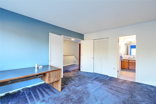 unfurnished bedroom with sink, a closet, ensuite bath, and dark colored carpet