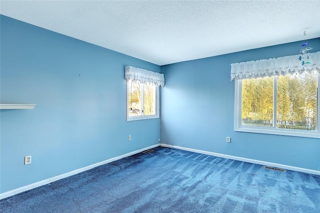 carpeted spare room with a textured ceiling