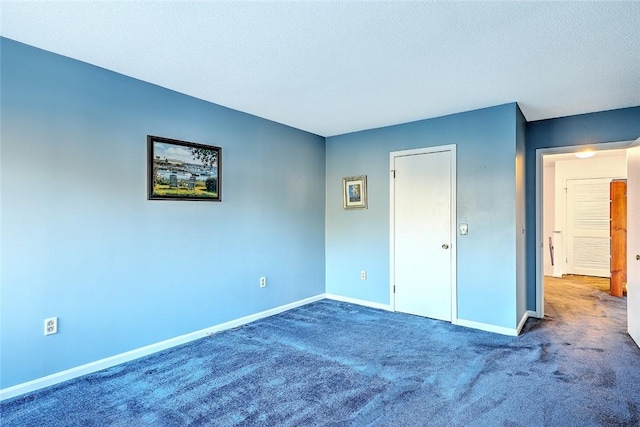 unfurnished bedroom with a textured ceiling and dark carpet