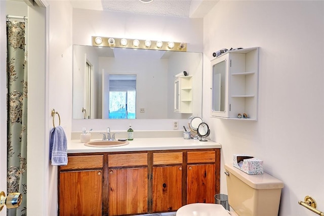 bathroom with vanity, toilet, and a textured ceiling