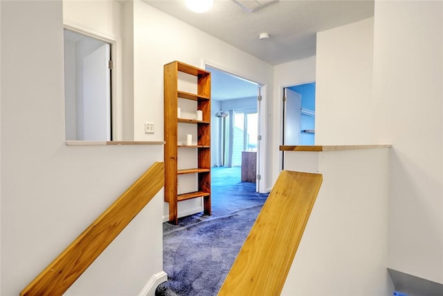 hall featuring a textured ceiling and carpet floors