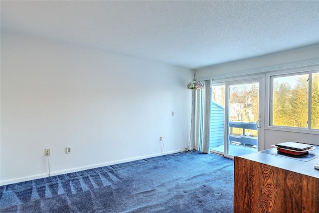 empty room with dark colored carpet and a textured ceiling