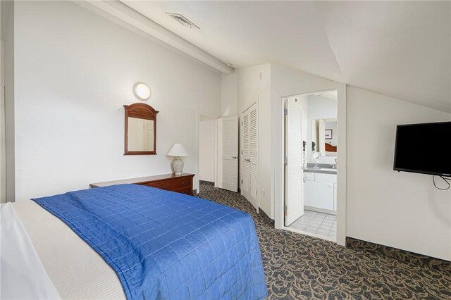 carpeted bedroom featuring vaulted ceiling with beams and ensuite bath