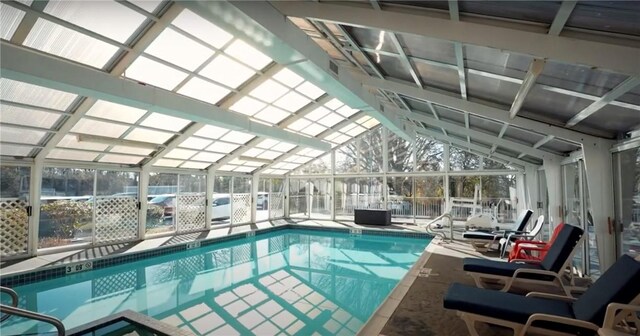 view of swimming pool featuring glass enclosure and a patio area