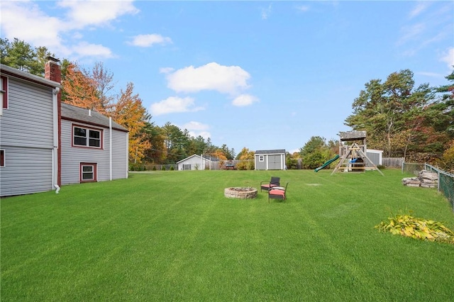 view of yard featuring a shed, a playground, and a fire pit