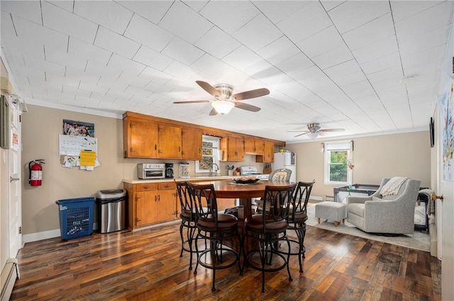 dining room with baseboard heating, crown molding, ceiling fan, and dark hardwood / wood-style floors