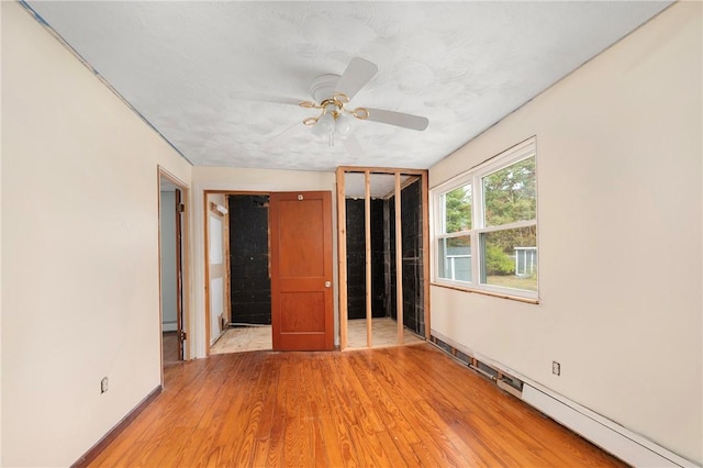 unfurnished bedroom with a textured ceiling, ceiling fan, a baseboard radiator, light hardwood / wood-style floors, and a closet