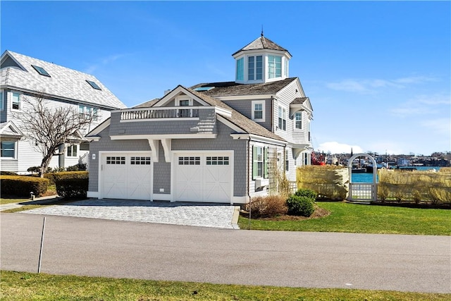 view of front of home featuring a balcony, a front lawn, and a garage