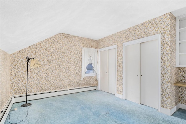 unfurnished bedroom featuring vaulted ceiling, multiple closets, carpet floors, and a baseboard radiator