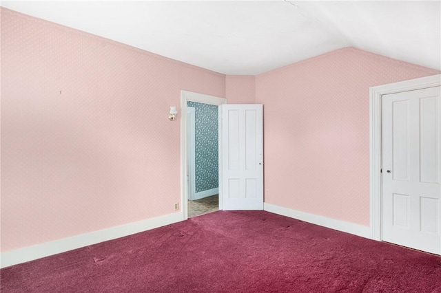 unfurnished bedroom featuring lofted ceiling and carpet floors