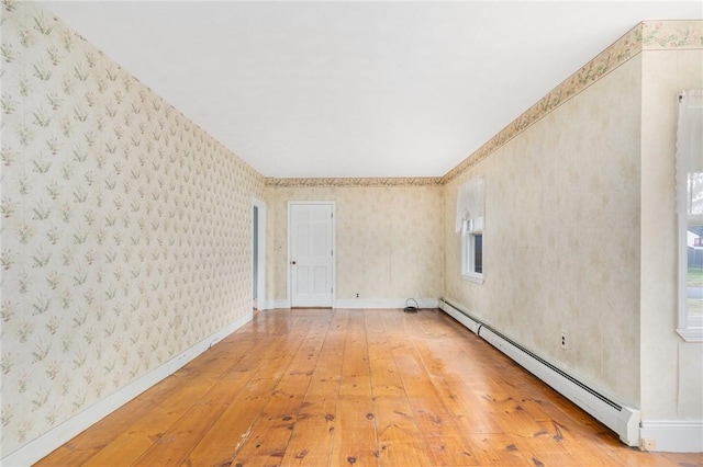 unfurnished room featuring wood-type flooring and a baseboard heating unit