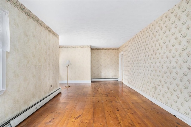 unfurnished room featuring wood-type flooring and a baseboard heating unit