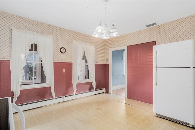 interior space featuring a notable chandelier, decorative light fixtures, a baseboard heating unit, and white refrigerator