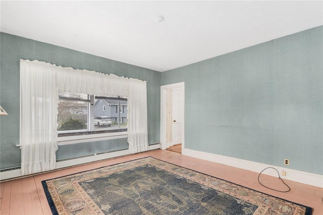 empty room featuring hardwood / wood-style floors and a baseboard heating unit