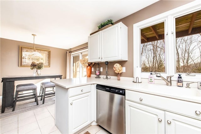 kitchen featuring white cabinets, stainless steel dishwasher, decorative light fixtures, light tile patterned flooring, and kitchen peninsula