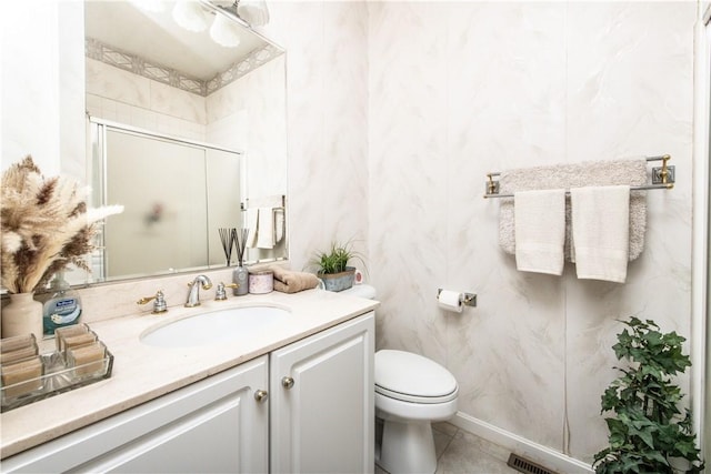 bathroom with tile patterned flooring, vanity, toilet, and a shower with door