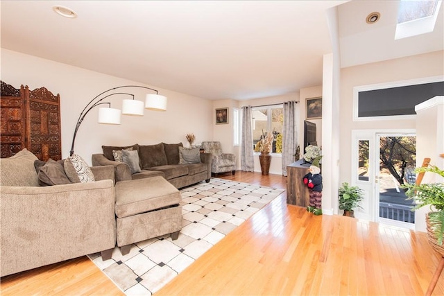 living room with a healthy amount of sunlight, wood-type flooring, and a skylight