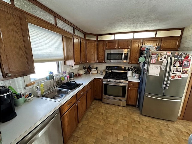 kitchen with tasteful backsplash, appliances with stainless steel finishes, sink, and a textured ceiling