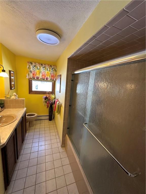 full bathroom featuring combined bath / shower with glass door, tile patterned flooring, vanity, a textured ceiling, and toilet