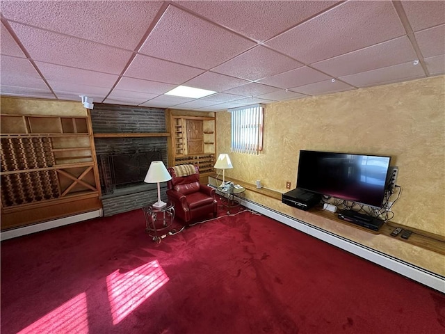 unfurnished room featuring a baseboard radiator, carpet floors, a drop ceiling, and a fireplace