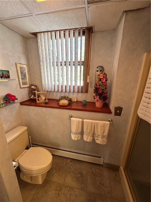 bathroom featuring a paneled ceiling, toilet, and a baseboard heating unit