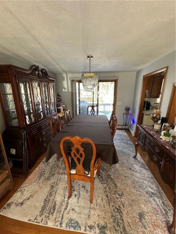 dining space with an inviting chandelier, wood-type flooring, and a textured ceiling