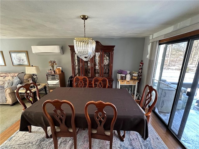 dining room featuring hardwood / wood-style flooring, a chandelier, a wall unit AC, and a textured ceiling