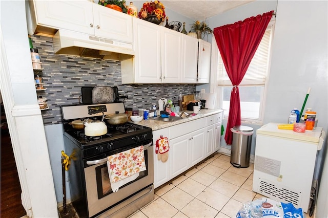 kitchen with decorative backsplash, light tile patterned floors, white cabinets, and stainless steel gas stove