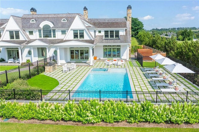 rear view of property featuring a fenced in pool and a patio