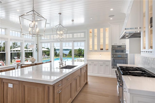 kitchen featuring sink, white cabinetry, an island with sink, and hanging light fixtures