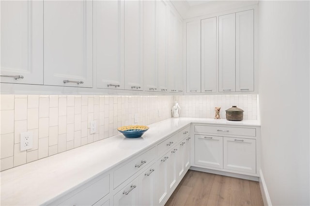 kitchen featuring decorative backsplash, white cabinets, and light wood-type flooring