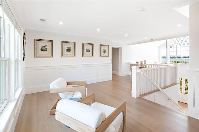 living area featuring crown molding and light hardwood / wood-style floors