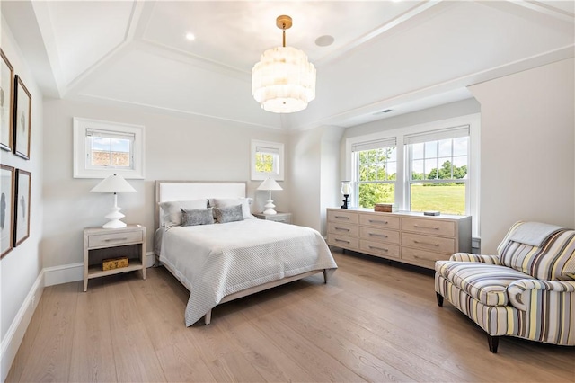 bedroom with a raised ceiling and light hardwood / wood-style flooring