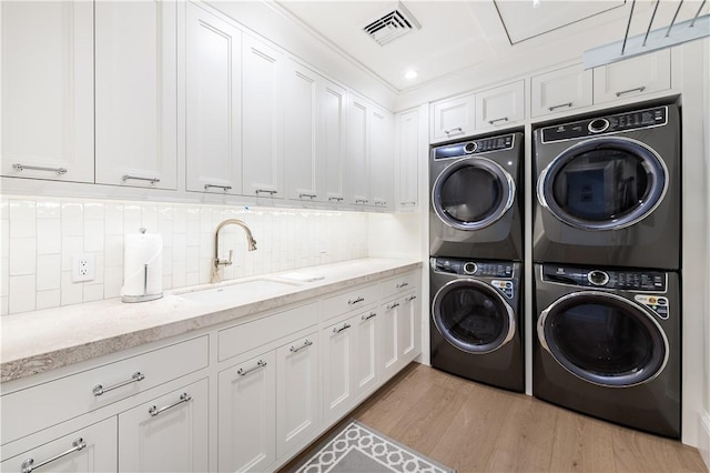 laundry area featuring cabinets, sink, stacked washer and clothes dryer, independent washer and dryer, and light hardwood / wood-style floors