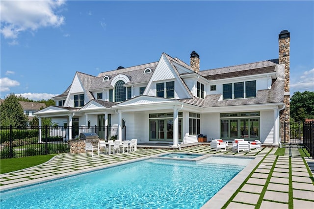 rear view of property featuring outdoor lounge area, a pool with hot tub, and a patio area