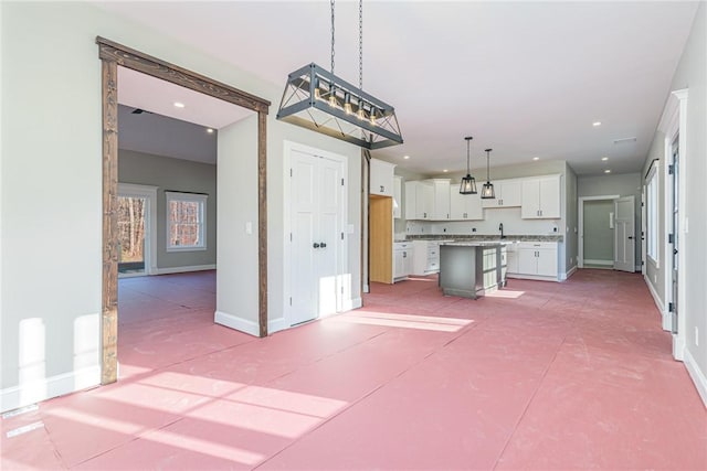 kitchen with a center island, sink, decorative light fixtures, a breakfast bar, and white cabinets