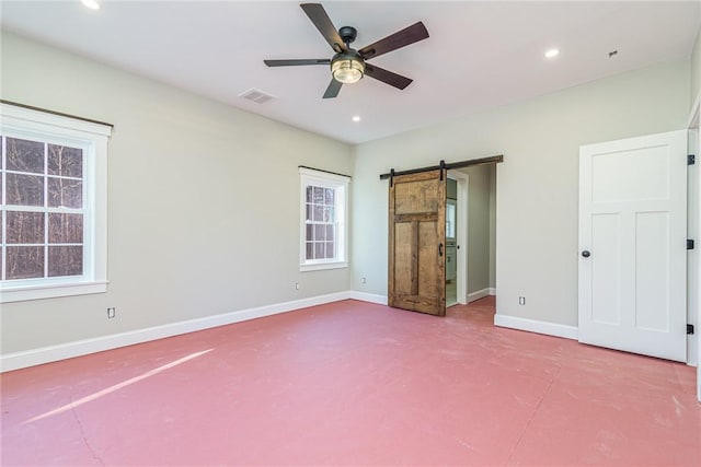 unfurnished bedroom with a barn door and ceiling fan