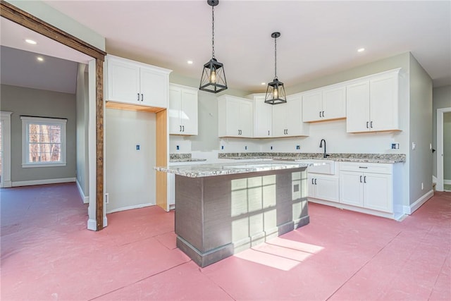 kitchen with pendant lighting, white cabinetry, a kitchen island, and light stone counters