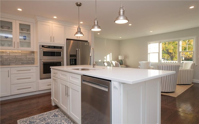 kitchen with white cabinets, pendant lighting, a center island with sink, and stainless steel appliances