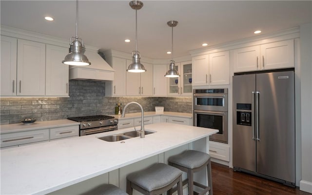 kitchen featuring backsplash, high end appliances, sink, white cabinets, and hanging light fixtures